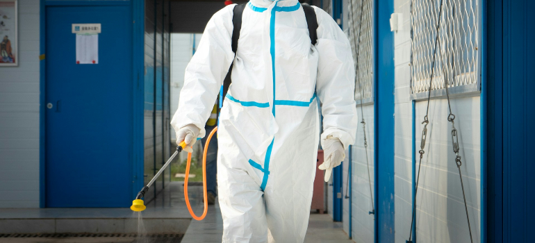 Osoba u zaštitnom odelu koja demonstrira kako se radi deratizacija